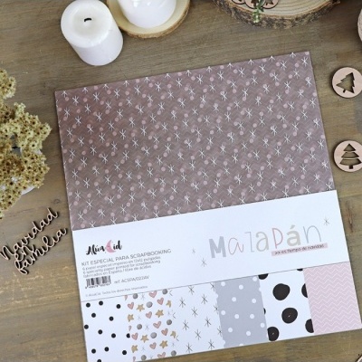 Kit de scrapbooking com padrões variados de papel sobre mesa de madeira com velas e enfeites