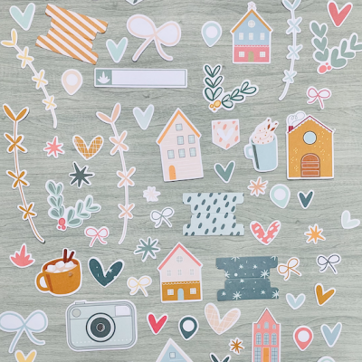 Autocolantes coloridos com temas de casas e corações num fundo de madeira clara