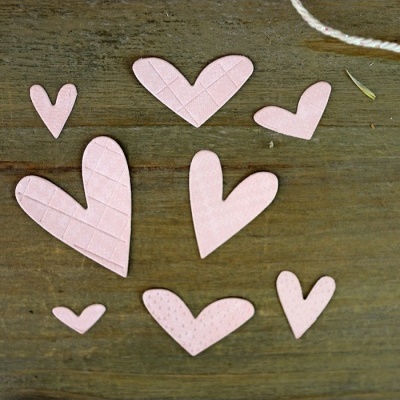 Sete corações cor-de-rosa de papel em várias texturas sobre madeira