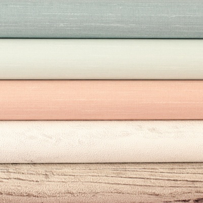 Tecidos empilhados em cores neutras e texturas suaves