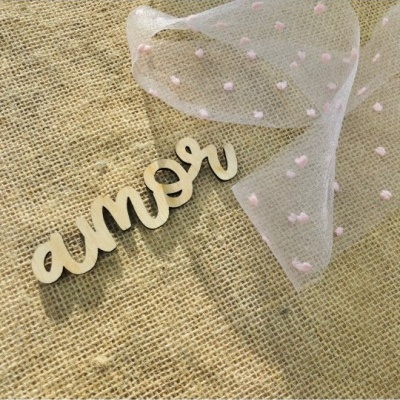 Palavra 'amor' em madeira sobre tecido de juta com fita transparente e pontos cor-de-rosa