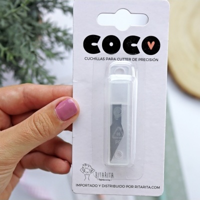 Pacote de lâmina para cutter de precisão COCO V em packaging branco segurado por mão com unhas rosas