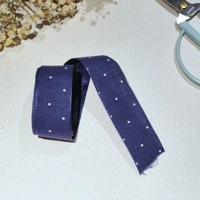 Fita de tecido azul com pontos brancos e tesoura