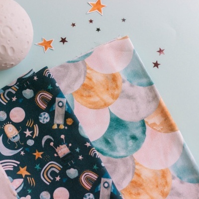 Tecidos estampados coloridos com padrão de unicórnios e escamas sobre fundo azul claro