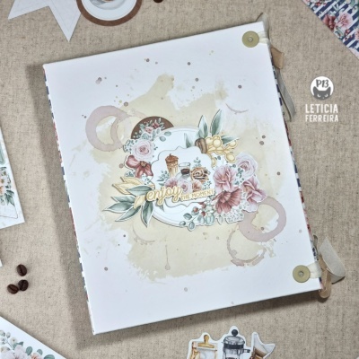 Álbum ou caderno com capa branca, flores e motivos de café em tons pastel sobre fundo bege.