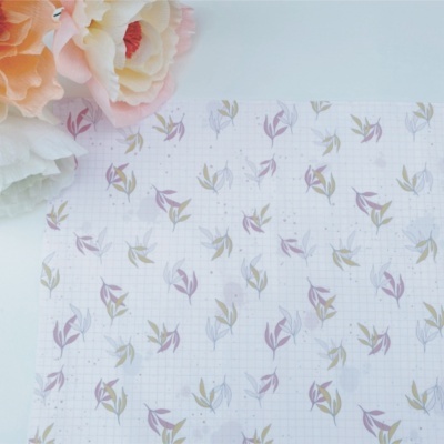 Papel de embrulho branco com padrão de folhas coloridas e flores artificiais ao lado