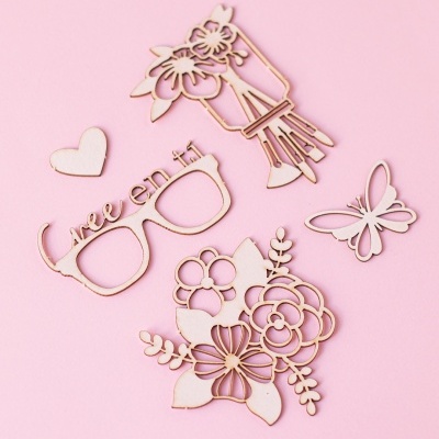 Recortes decorativos em madeira clara sobre fundo rosa