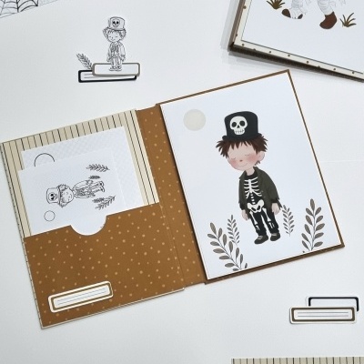 Papelaria de Halloween com pretos e castanhos, ilustrações de esqueletos em papel e recortes