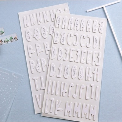 Letras adesivas em relevo brancas em tabuleiros sobre fundo azul claro