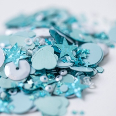 Lantejoulas azuis de várias formas sobre fundo branco