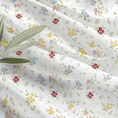 Tecido branco com pequenas flores coloridas e uma folha verde