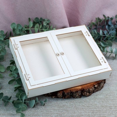 Caixa organizadora branca em madeira com tampa dupla sobre base de madeira rústica e folhas verdes