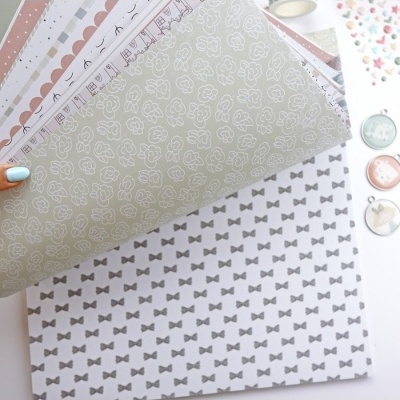 Folhas de papel decorativo com padrões de flores e laços em tons pastéis