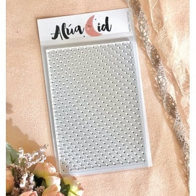 Pack de pedras autocolantes prateadas em embalagem Alúa Cid com flores e tecido ao fundo