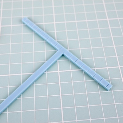 Gabarito azul em forma de T sobre fundo quadriculado verde.