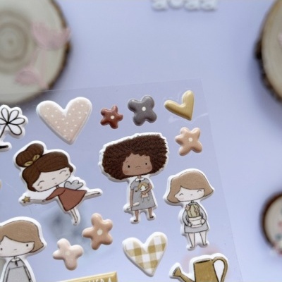 Autocolantes com desenhos de raparigas cartoon, corações e flores em várias cores sobre cartolina translúcida.