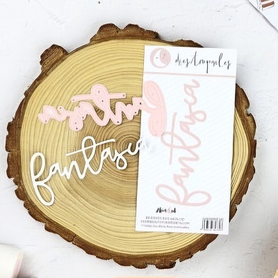 Recorte em acrílico com palavra fantasia em rosa e branco sobre base de madeira redonda