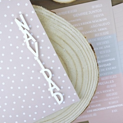 Cartão cor-de-rosa com bolinhas brancas e letras NAÍPAD sobre madeira clara