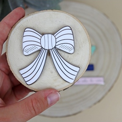 Broche laço branco com linhas pretas sobre disco de madeira