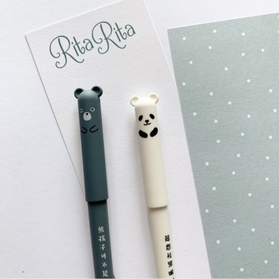 Canetas com tampas de urso e panda sobre cartão e papel com padrão de pontos