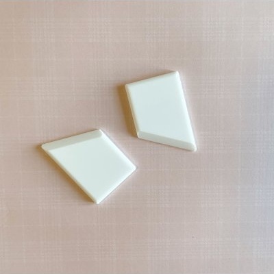 Dois objetos brancos geométricos sobre superfície cor de rosa com padrão