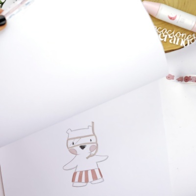 Livro aberto com ilustração de animal vestido, caneta e adereço em madeira ao fundo