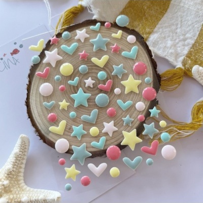 Conjunto de autocolantes estampados com estrelas e corações coloridos em tons pastel sobre madeira redonda