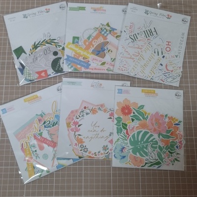 Pacotes de elementos de papel para scrapbooking com temas florais sobre superfície quadriculada