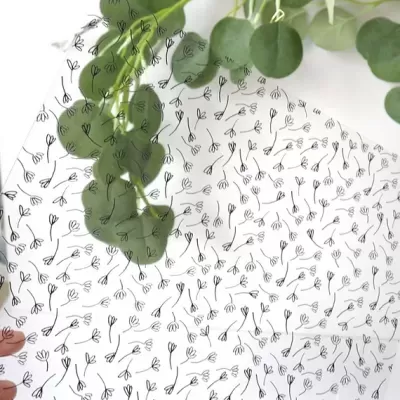 Folha transparente com padrão de raminhos pretos e folhas verdes ao fundo