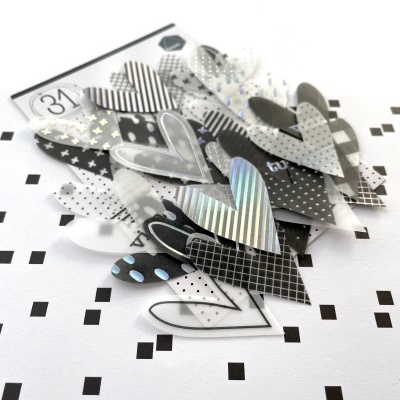 Vários corações decorativos em preto, branco e prateado com padrões variados sobre fundo branco com quadrados pretos.