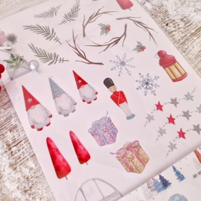 Folha de autocolantes natalícios com vários desenhos e cores sobre mesa de madeira