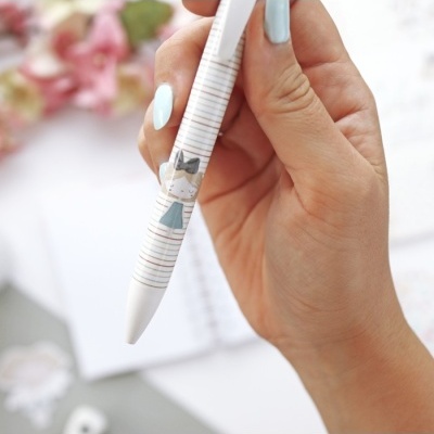 Caneta branca com ilustração de menina em fundo desfocado