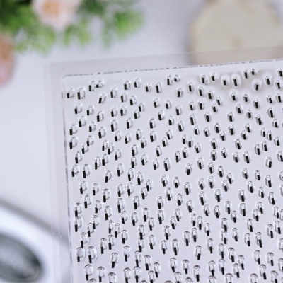 Folha transparente com pequenos elementos pretos e brancos dispostos em padrão repetitivo