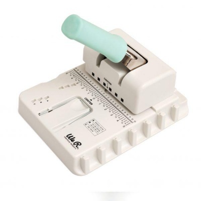 Máquina perfuradora manual branca com alavanca azul clara e escala de medidas.