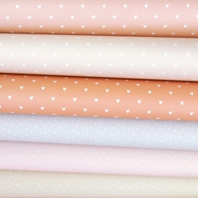 Tecidos em tons pastel com padrões de corações e pontos brancos dobrados