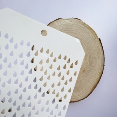 Placa branca com recortes de gotas sobre madeira circular