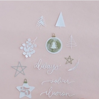 Adesivos decorativos de Natal com árvores, estrelas, ramos e palavras em fundo rosa claro.