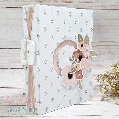 Álbum de scrapbook branco com decoração de flores em tons rosa e castanho e encadernação com argolas plásticas e cordões de sisal