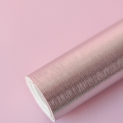 Rolo de papel de parede rosa com textura fina sobre fundo rosa claro