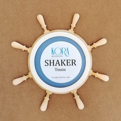 Shaker em formato de timão de madeira clara com etiqueta azul e branca no centro