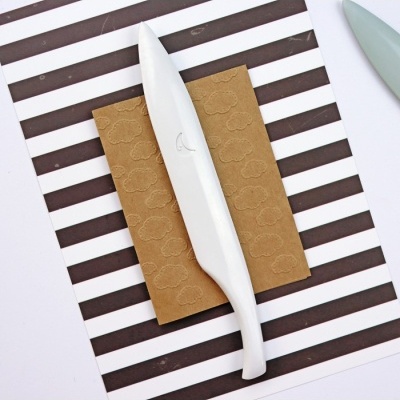 Faca branca sobre fundo riscado castanho e branco com papel castanho texturado