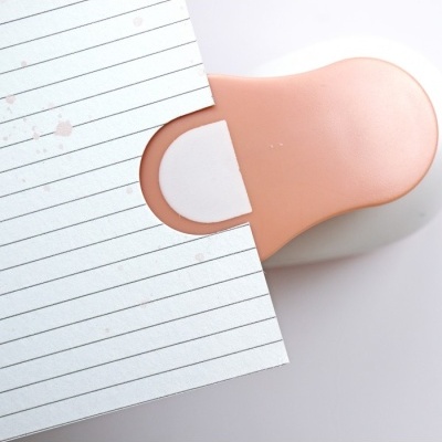 Recortador de papel com pega cor de pele e disco branco junto a folha de papel com linhas pretas