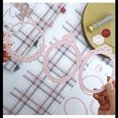Três molduras decorativas cor de rosa em formas ovais e circulares com detalhes, seguradas por mãos femininas
