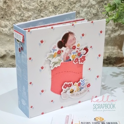 Álbum de scrapbook decorado com bolso vermelho e flores em fundo branco com padrão de pequenas flores vermelhas