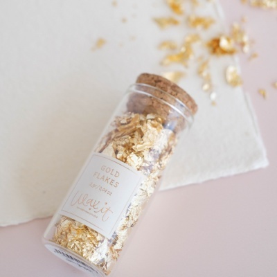 frasco de vidro com tampa de cortiça contendo folhas douradas com etiqueta branca