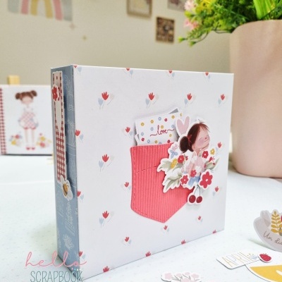 Álbum de scrapbook com design floral e recortes decorativos sobre mesa branca