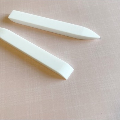 Duas ferramentas brancas alongadas sobre tecido rosa claro quadriculado