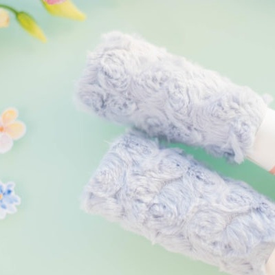 Dois rolos de fita azul claro com padrão floral em relevo sobre fundo azul e flores decorativas.