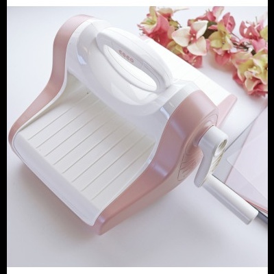 Dispositivo manual de corte branco e rosa com alavanca e flores cor-de-rosa ao fundo