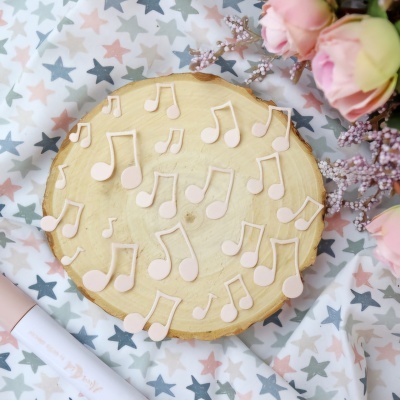 Notas musicais rosas sobre madeira com flores e tecido de estrelas